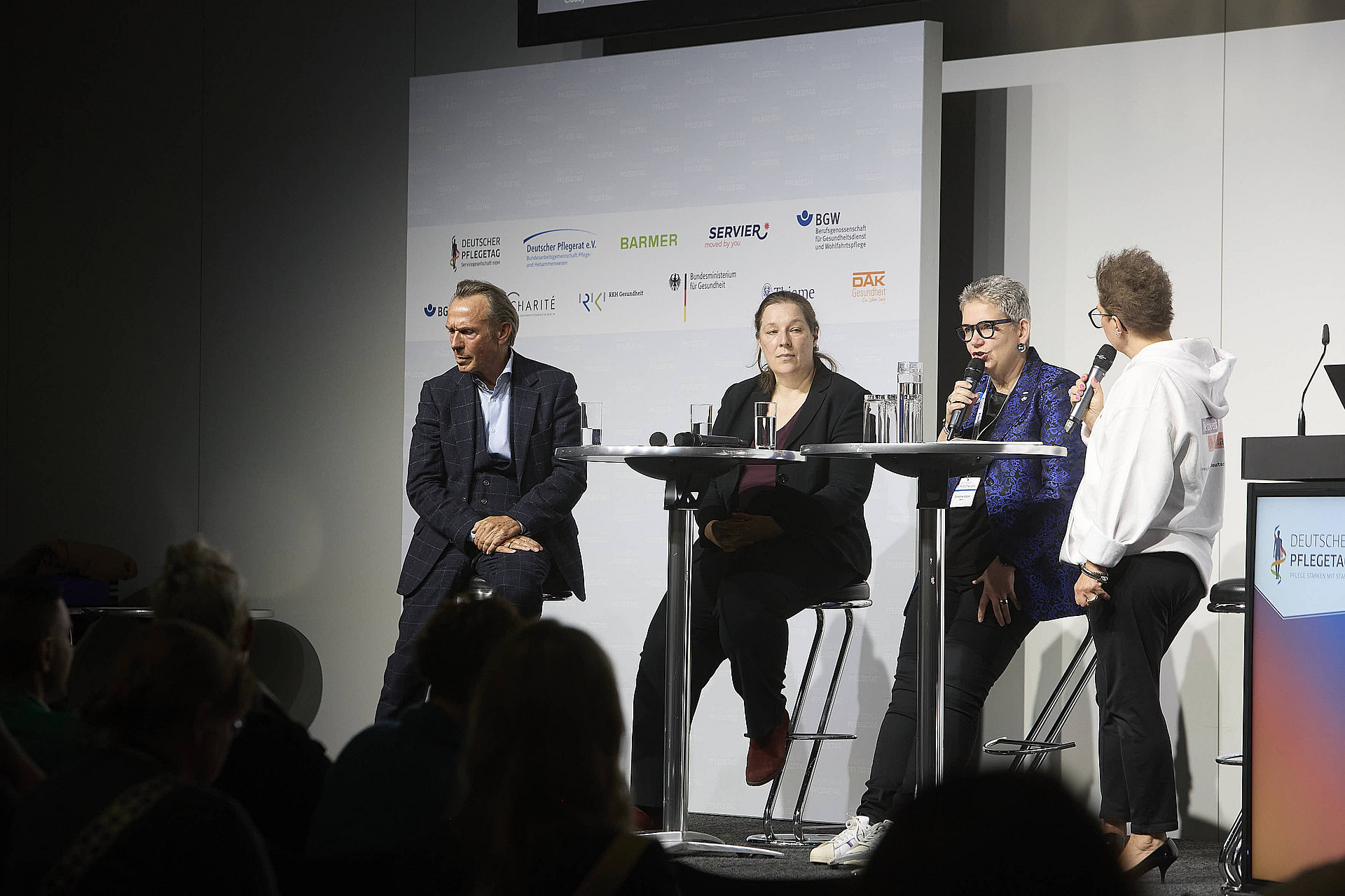 Vier Personen auf einer Bühne unterhalten sich vor Publikum.