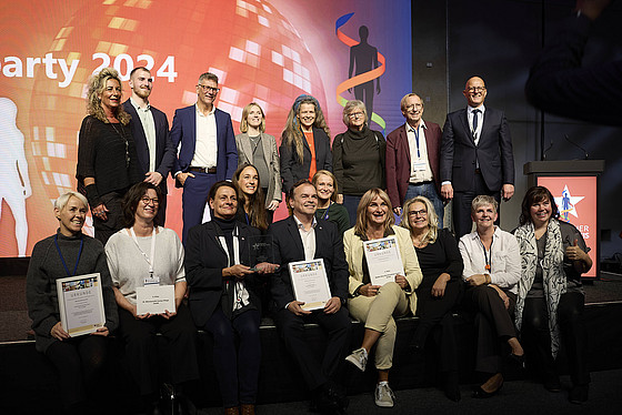 Menschen auf einer Bühne. Halten Bilderrahmen mit Auszeichnung hoch.