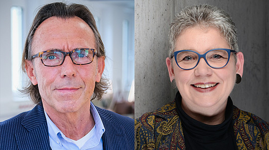 Ein Mann und eine Frau mit Brille sind in einem nebeneinanderstehenden Porträt zu sehen. Der Mann hat schulterlanges Haar und trägt einen Anzug. Die Frau hat kurzes, graues Haar und trägt eine bunte Brille und ein gemustertes Outfit. Beide lächeln leicht.