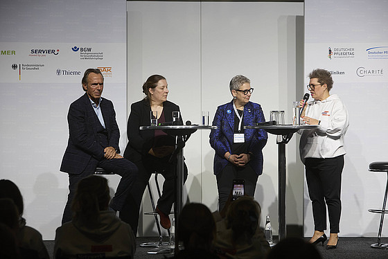 Vier Personen auf einer Bühne unterhalten sich vor Publikum.