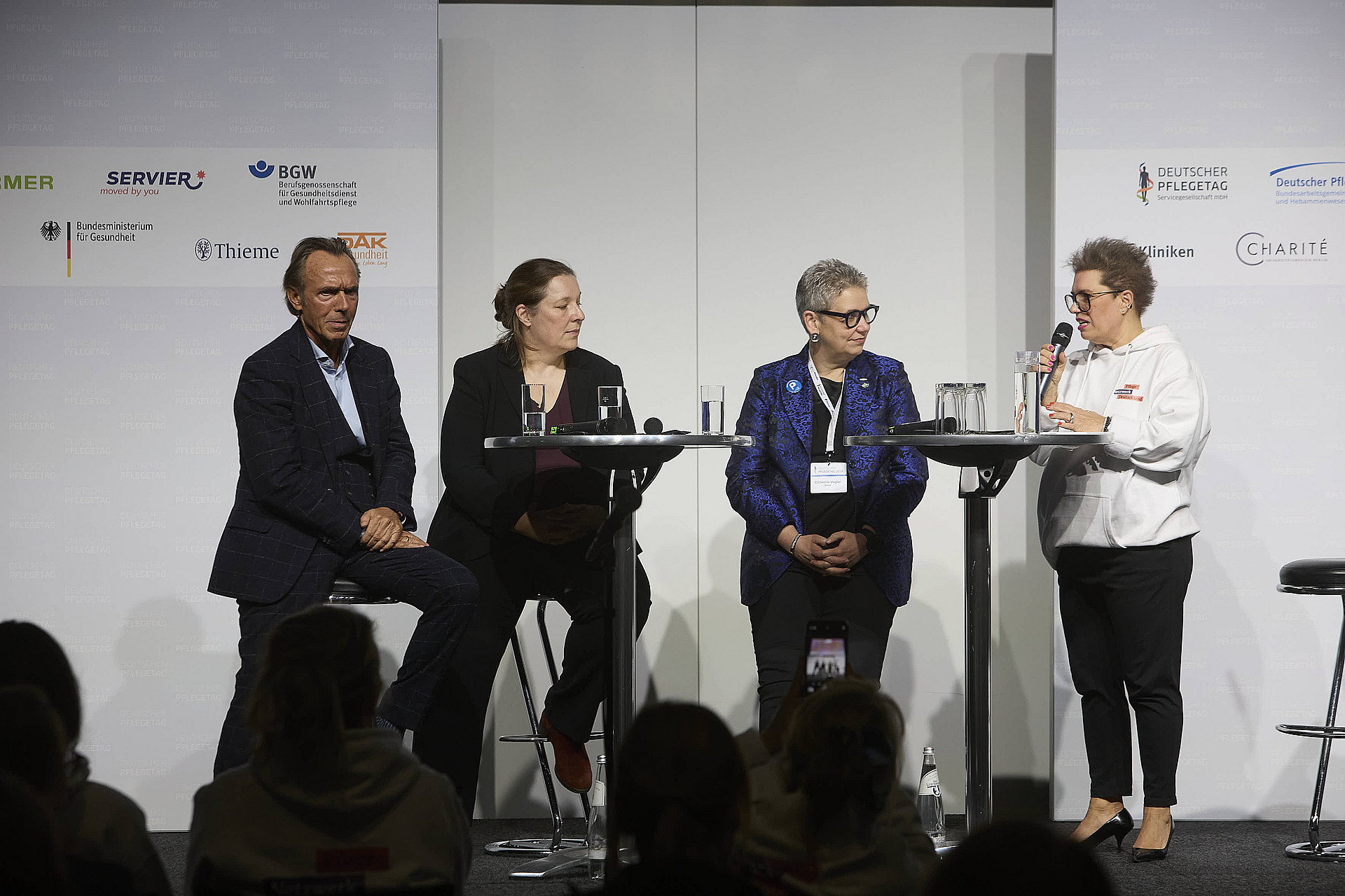 Vier Personen auf einer Bühne unterhalten sich vor Publikum.