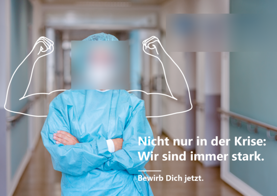 Ein medizinischer Mitarbeiter im Kittel steht mit verschränkten Armen im Flur eines Krankenhauses. Daneben sind illustrierte starke Arme gezeichnet. Der deutsche Text lautet: „Nicht nur in der Krise: Wir sind immer stark. Bewirb Dich jetzt.“ Übersetzung: „Nicht nur in der Krise: Wir sind immer stark. Bewerben Sie sich jetzt.“