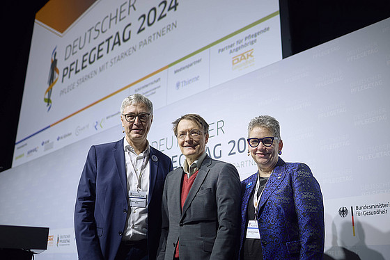Zwei Männer und eine Frau auf der Bühne beim Deutschen Pflegetag 2024.